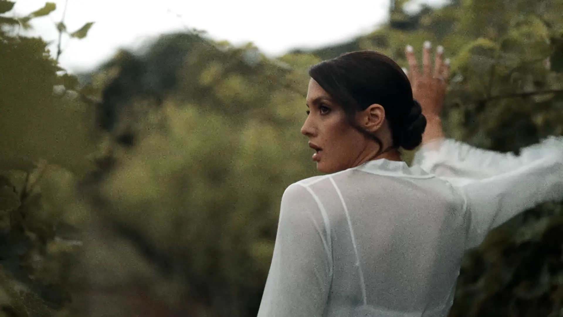 A bride standing in a field, seen from behind